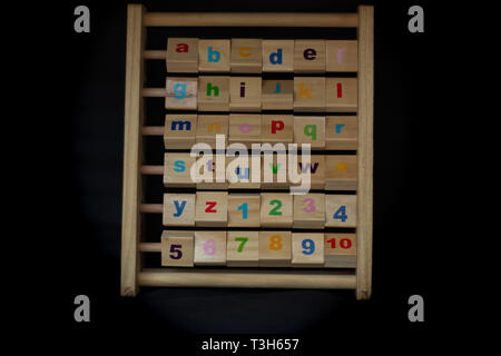 Holz Spielzeug des alapbet und Zahlen in einem schwarzen Hintergrund. Stockfoto