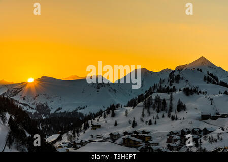 Orange Himmel und die Sonne über die Berge in Obertauern, Österreich Stockfoto