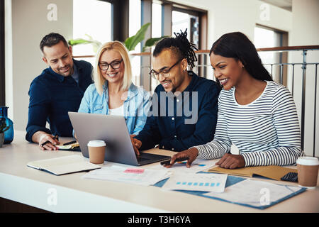 Gruppe von verschiedenen Geschäftsleute sitzen zusammen in eine Zeile in einer Tabelle über Business und lächelnd, während an einem Notebook arbeitet Stockfoto