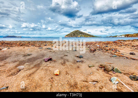 Strand Meer Sand Steine und eine Insel in einer stürmischen und trübe Winter Tag Stockfoto