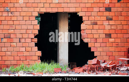 Gebrochener roter Mauer mit einem großen Loch und ein Bau Spalte Säule in der Mitte Stockfoto