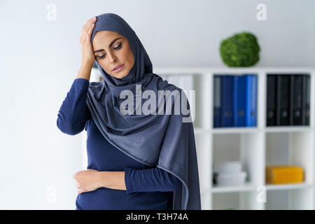 Muslimische Frau, die Kopfschmerzen Stockfoto