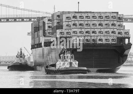 Schwarz-weiß-Foto von Schleppern, die das Containerschiff HORIZON RELIANCE unter der Vincent Thomas Bridge im Hafen von Los Angeles, USA, führen Stockfoto