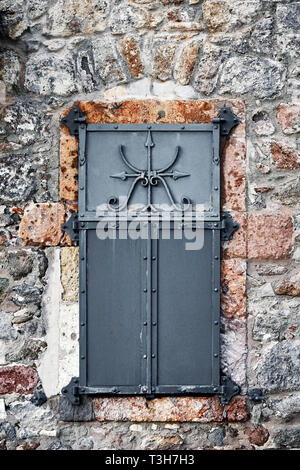 Vintage Fenster mit schwarzem Eisen Shutter und Steinmauer eines antiken Hauses Stockfoto