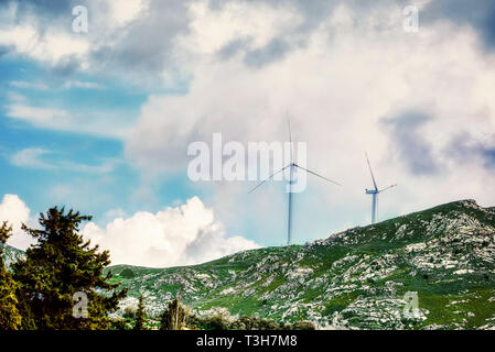 Windkraftanlagen auf der Bergspitze gegen einen bewölkten Himmel Hintergrund Stockfoto