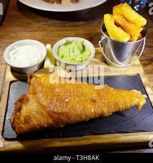 Fisch und Chips mit Tartar Sauce und Erbsenpüree serviert. Das Bier zerschlagene Fisch war in Grimsby gelandet. Stockfoto