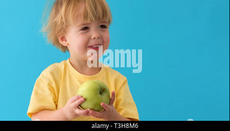 Kleiner Junge hält einen großen grünen apple Stockfoto