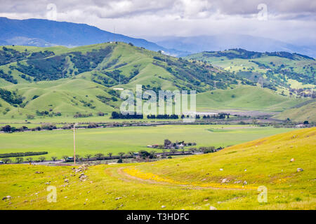 Grüne Hügel und das Tal in South San Francisco Bay Area an einem regnerischen Frühlingstag; Wanderweg im Vordergrund sichtbar; San Jose, Kalifornien Stockfoto