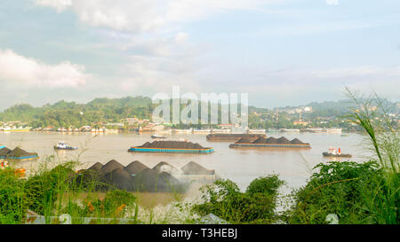 Der Verkehr von tugboat ziehen Lastkahn voller Steinkohle zu den Mahakam Fluss, Samarinda, Indonesien. Industrie und Bergbau Hintergrund Stockfoto