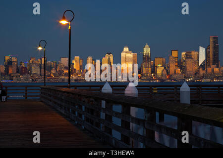 WA16115-00...WASHINGTON - die untergehende Sonne sorgt bei Sonnenuntergang im Seacrest Park an den Ufern der Elliott Bay, 2018, für ein Leuchten auf den Hochhäusern in Seattle. Stockfoto