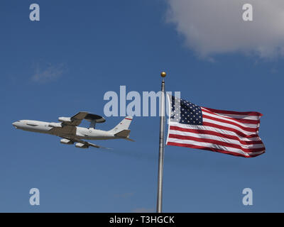 Eine E-3G Airborne Warnung und Steuerung Flugzeuge der 552Nd Air Control, Air Combat Command, im Flugzeug, während die Durchführung von Pilot proficiency Training mit der amerikanischen Flagge im starken Wind im Vordergrund fliegen am März 20, 2019, Tinker Air Force Base, Oklahoma. Die 552Nd ACW ist bekannt als "America's Wing" und deren E-3 AWACS Tinker AFB Home seit 23. März 1977 genannt haben. (U.S. Air Force Foto/Greg L. Davis) Stockfoto