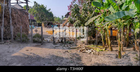 Die Außenseite des traditionellen kambodschanischen Häuser im Dorf entlang den Fluss Mekong mit landwirtschaftlichen Produkten und Tools. Stockfoto