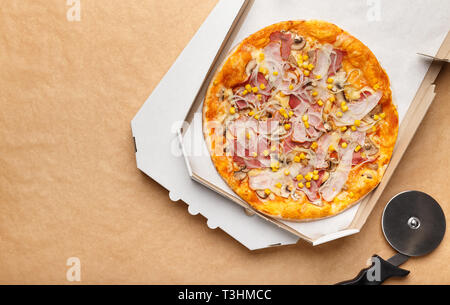 Pizza in Lieferung und Cutter auf hölzernen Hintergrund Stockfoto