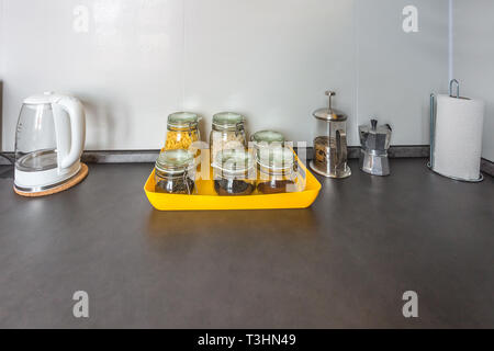 Glas stilvolle vintage Gläser mit verschiedenen Speisen und Teekanne im Inneren der modernen Küche im Loft Wohnung Wohnung im minimalistischen Stil mit Gelb c Stockfoto