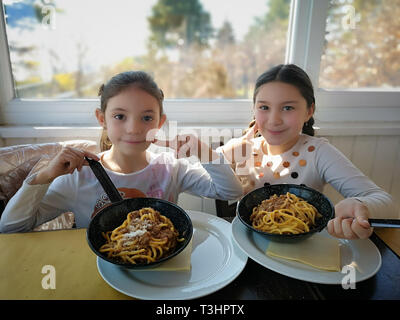 Verona, Italien - 17. März 2019: Kleine Mädchen essen Spaghetti mit Soße serviert direkt in der Pfanne. Stockfoto