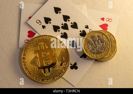 Bitcoins zur Festlegung auf den Tisch mit einem Bündel von Münzen und Karten im Hintergrund. Spielende on-line-Konzepte. Stockfoto