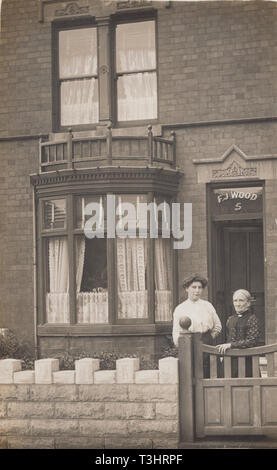 Jahrgang 1913 Photographische Postkarte zeigt zwei Damen Stand an der vorderen Tor Nr. 5 Swanage Straße, Kleine Heide, Birmingham, Warwickshire, England. Zeichen, F. J. Holz. Stockfoto