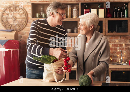 Senior Paar auspacken Einkaufstaschen in der Küche Stockfoto