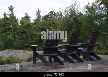 Muskoka oder Adirondack Stühle am Ende der Pier mit Blick auf einen großen blauen See mit einem blauen Himmel Stockfoto