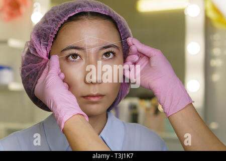 Microbleeding Augenbrauen und Architektur. Kosmetikerin Schaltung erzeugt und Symmetrie Augenbrauen. Kosmetische Verfahren in Spa Salon Stockfoto