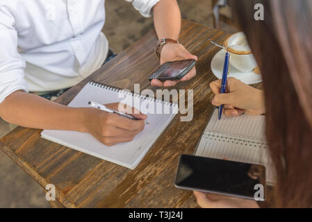 Weibliche und männliche Hände halten Telefon und schreiben Hinweis Stockfoto