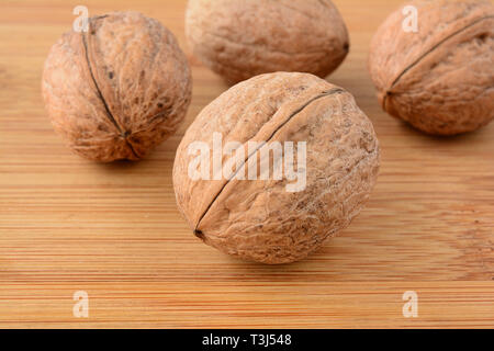 Wallnuts über Holz, eine im Vordergrund und drei im Hintergrund, Hintergrund, Nahaufnahme, geringe Tiefenschärfe Stockfoto