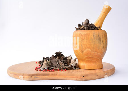 Getrocknete genießbare, aromatische Horn auf viel Pilze mit rotem Pfeffer in bambus holz- Mörtel, auf Bambus Schneidebrett, auf weißem Hintergrund Stockfoto