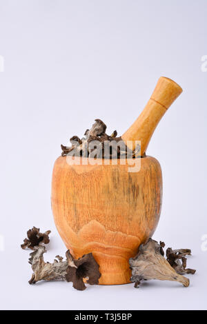 Getrocknete Füllhorn Pilze in bambus holz Mörser mit Pistill auf weißem Hintergrund Stockfoto