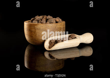 Menge ganze braune Ton Steine (leca) mit Houten und hölzerne Schaufel auf schwarz Glas isoliert Stockfoto