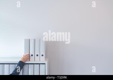 Hand erreichen für Dokument Ring Binder auf Büro Regal, Geschäftsfrau, Datei, Ordner mit Dokumentation, viel leerer weißer Raum kopieren Stockfoto