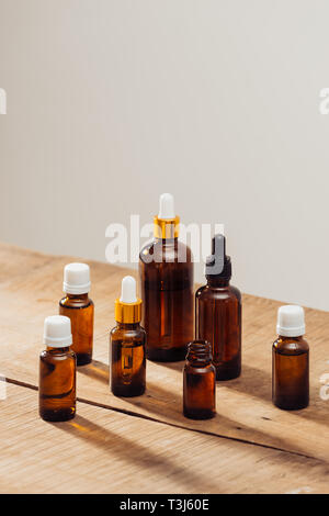 Ätherische Öle Flaschen auf hölzernen Schreibtisch mit Kerzenschein neben. Spa Wellness gesetzt. Stockfoto