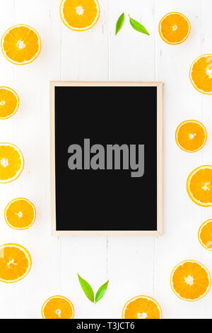 Kreative skandinavischen Stil flach Blick von oben auf die frisch gepressten Obst Schichten auf weissem Holztisch Hintergrund mit blackboard Frame mockup. Minimale summ Stockfoto
