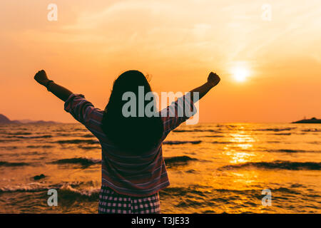Erfolg oder Freiheit Konzept. Mädchen steigen zwei Hand bei Sonnenuntergang Meer. Stockfoto