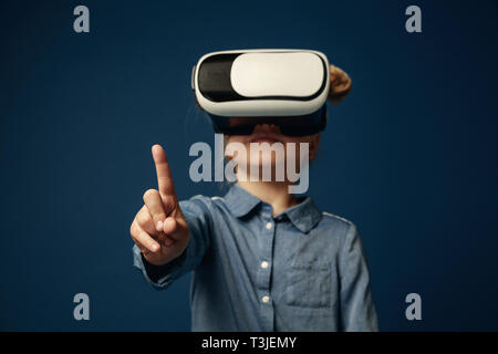 Reisende der Zukunft. Kleines Mädchen oder Kinder, die auf den leeren Raum mit Virtual reality Brillen auf Blau studio Hintergrund isoliert. Konzept der Spitzentechnologie, Videospiele, Innovation. Stockfoto