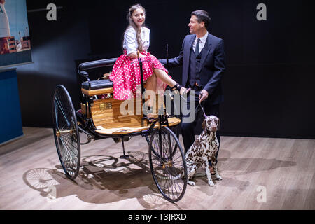 Essen, Deutschland. 10 Apr, 2019. Die Modelle Laura und Olaf, sowie Hund Fritzi, stand vor dem Benz Patent-Motorwagen I, das erste Auto von 1886, auf der Techno Classica für Oldtimer und Youngtimer. Die Messe findet vom 10. bis 14. April. Credit: Marcel Kusch/dpa/Alamy leben Nachrichten Stockfoto