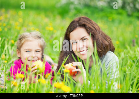 Mutter und Tochter Äpfel essen auf der grünen Wiese Stockfoto