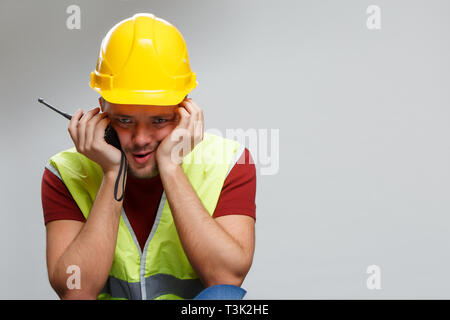 Foto von umgekippt Builder in gelben Helm mit Walkie-talkie. Stockfoto