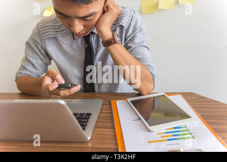 Asiatische Geschäftsmann mit Smartphone und Laptop im Büro Stockfoto