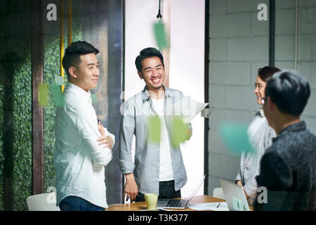 Glückliche junge asiatische Unternehmer Team plaudern während der Sitzung im Büro. Stockfoto