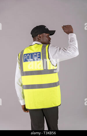 Salisbury, Wiltshire, UK, April 2019. Rückansicht eines Polizisten in reflektierende Jacke und den rechten Arm erhoben. Stockfoto