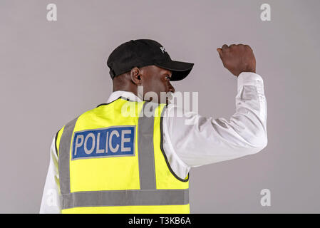 Salisbury, Wiltshire, UK, April 2019. Rückansicht eines Polizisten in reflektierende Jacke und den rechten Arm erhoben. Stockfoto