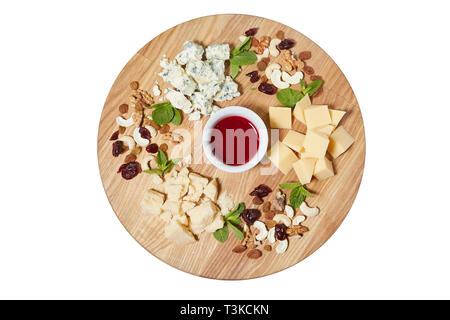 Käseplatte Antipasti Snack mit gemischtem italienischen Käse, Cashew, frischen Minzblättern, Walnüssen, Rosinen auf hölzernen Servierbrett auf weißem Hintergrund, Stockfoto