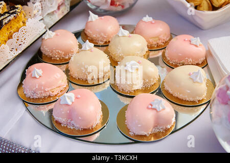Moderne französische Mousse Kuchen mit rosa Spiegelglasur in Form eines Herzens auf einem Tisch. Grußkarte zum Valentinstag oder Geburtstag. Kuchen in Form eines W Stockfoto