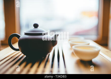 Teekanne und Tassen mit chinesischem Tee in der Nähe der Fenster auf den Tisch für die Teezeremonie Stockfoto