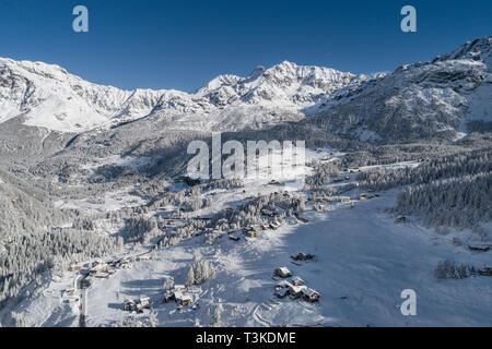 Alpine Dorf und Wald im Winter, Blick auf die Alpen Stockfoto