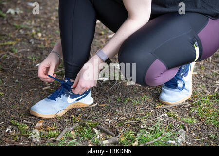 Junge Frau trainer Schnürsenkel binden, bevor sie für einen Lauf Stockfoto