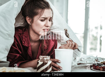 Deprimiert Frau essen eine Menge Süßigkeiten Stockfoto