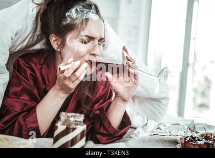 Deprimiert Frau trinkt Rauchen und Essen viel Stockfoto