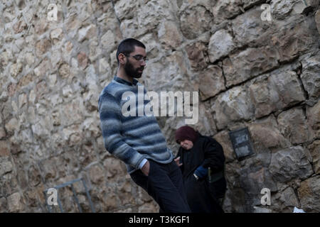 Ein israelischer Mann geht vorbei an einer palästinensischen Frau betteln auf der Straße in Jerusalem, Israel, 15.03.19. Stockfoto