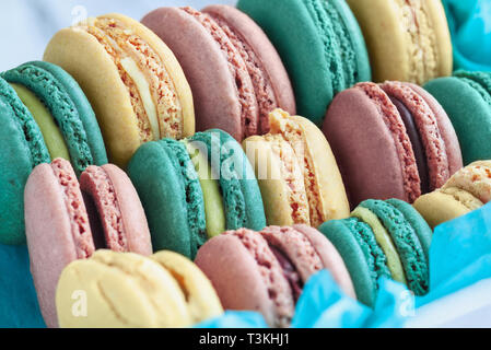 Sortiment frische französische Macarons in einer hübschen blauen Papier mit unscharfen Hintergrund verpackt.. Stockfoto